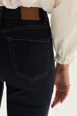 Jean de mezclilla azul marino, tiro medio, con silueta ligeramente acampanada desde la rodilla.