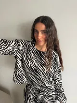 Remera manga larga de viscosa con estampado animal print tipo cebra en blanco y negro, corte holgado y cuello redondo. Presenta un pequeño parche cuadrado bordado en el pecho.