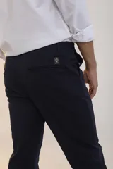 Pantalon de corte recto y ajuste slim, color azul marino, con cierre de botón y cremallera, bolsillos laterales y traseros.
