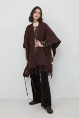 Ruana de tejido de punto en color marrón chocolate, con diseño abierto, corte amplio y terminación con flecos en el ruedo.