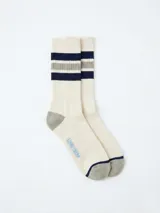 Medias de caña media en color crema, con diseño de rayas horizontales en azul marino y gris en la parte superior. Presentan puntera y talón en color gris, con la palabra 'UNIFORM' bordada en azul claro en el lateral.