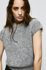 Jersey de punto gris jaspeado con cuello redondo y manga corta. Presenta detalles de encaje en los laterales.