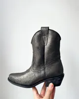 Botas estilo tejano de cuero vacuno con acabado brillante en tono grafito. Presentan un diseño clásico con costuras decorativas en el empeine, caña media y taco bajo.