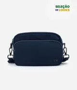 Cartera bandolera de tamaño pequeño, confeccionada en poliéster con estructura ligeramente acolchada. Presenta un diseño minimalista en color azul marino con un bolsillo frontal con cierre y detalle de logo STN en relieve. Incluye correa ajustable y cierre principal doble.