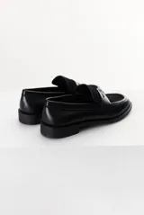 Mocasín color marrón claro, con capellada de cuero liso y aplique de gamuza en marrón oscuro. Tiene punta redondeada y suela plana de goma negra.