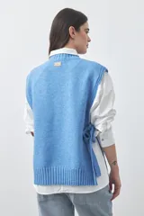 Chaleco tejido de punto con silueta relajada y diseño sin mangas. Presenta lazos laterales ajustables y cuello redondo.
