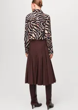 Camisa de poliéster con estampado animal print tipo cebra en tonos negro, marrón y beige, manga larga y cuello camisero clásico.