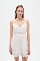 Vestido corto blanco de algodón con diseño de broderie, escote en V y tirantes finos. Presenta detalles de encaje y botones frontales.