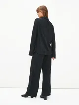 Camisa negra con textura plisada, cuello clásico, escote en V y mangas largas.