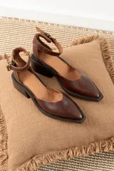 Zapatos de cuero color chocolate con diseño de punta cuadrada, taco bloque bajo y tira ajustable al tobillo con hebilla metálica.