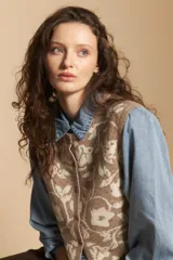 Chaleco tejido de punto con diseño floral ornamental, de silueta recta y cierre frontal con botones. Presenta una estética romántica y sofisticada, ideal para superponer sobre otras prendas.