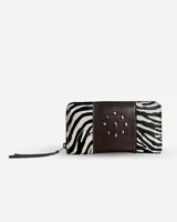 Billetera rectangular de cuero con cierre perimetral y tirador de flecos. Presenta un diseño combinado con paneles laterales de cuero vacuno con pelo estampado animal print de cebra y una franja central de cuero marrón oscuro decorada con tachas metálicas circulares.