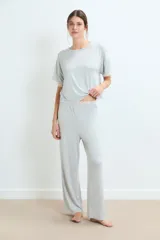 Pijama de dos piezas en color gris melange, compuesto por una remera de manga corta con detalles de encaje en los bordes y un pantalón de corte recto con cintura elástica y detalle de encaje en la pretina.