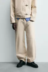 Jeans de hombre color beige claro, tiro medio, corte balloon fit con pierna relajada que se estrecha ligeramente hacia el bajo. Confeccionados en denim rígido de algodón, con cinco bolsillos y cierre frontal de cremallera y botón.