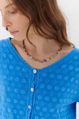 Camisa celeste de algodón con textura arrugada y bordados a tono, escote amplio, mangas largas y botones frontales.