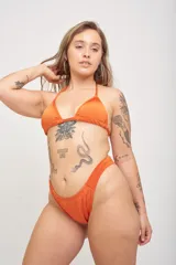 Conjunto de bikini color naranja, con corpiño triangular con copas removibles y tiras para atar, y bombacha clásica.