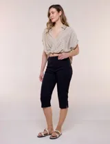 Pantalón capri blanco de tiro alto, corte entallado y silueta ajustada, con pretina ancha elastizada sin cierres, bolsillos simulados al frente y pequeños tajos en los ruedos.