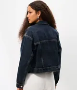Campera de jean con corte boxy, cuello clásico, cierre frontal con botones metálicos, bolsillos con solapa en el pecho y costuras reforzadas.