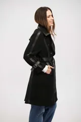 Tapado negro de corte cruzado con detalles en cuero sintético en solapas, puños y cierre frontal. Incluye cinturón ajustable con hebilla y botones metálicos.