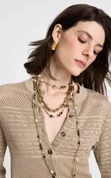 Cárdigan de punto beige con diseño calado y texturizado. Presenta cuello redondo, mangas largas y cierre frontal con botones a tono.