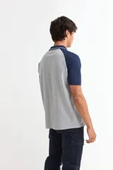 Remera tipo polo de manga corta con diseño combinado, presentando cuerpo en color azul marino y mangas y cuello en color gris. Cuenta con cierre frontal de botones.