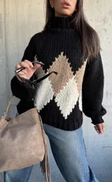 Polerón de tejido grueso con cuello alto, diseño de rombos en tonos negro, beige y blanco, y mangas largas con puños ajustados.