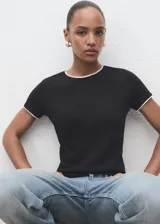 Camiseta de manga corta en color negro, con cuello redondo y bordes en contraste color blanco. Presenta un diseño recto y ajustado.