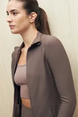 Campera deportiva de textura acanalada, color negro, con cierre frontal, cuello alto y mangas largas con orificio para el pulgar.