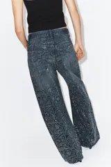 Jeans de tiro medio con corte baggy y cinco bolsillos. Presenta un diseño de estampado floral realizado con aplicaciones de strass a contraste sobre el tejido denim.