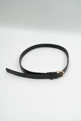 Cinturón fino de color negro con textura tipo cocodrilo y hebilla metálica dorada.