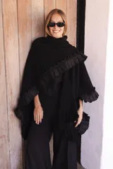 Ruana artesanal de lana merino en color marrón oscuro, con diseño tejido de textura marcada, detalles de volados laterales y flecos en el ruedo.