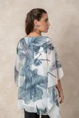 Blusa tipo túnica de gasa semitransparente con escote en V. Presenta un diseño fluido con estampado artístico de flores en tonos azules y grises sobre fondo blanco.