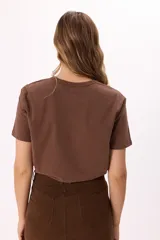 Remera marrón de algodón con cuello redondo y estampado frontal con la frase 'MIDTOWN MANHATTAN 1997' en color rosa.