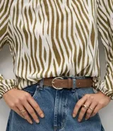 Blusa de viscosa con estampado animal print de cebra en tonos verde oliva y blanco, con escote bote y mangas largas abullonadas con puños elásticos.