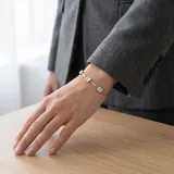 Pulsera de cadena fina de acero con tres dijes cuadrados engastados con circonias blancas.