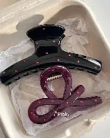 Set de dos clips para el pelo: uno azul con lunares rojos y otro rojo con forma de moño.