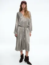 Vestido camisero de corte midi con diseño tipo kimono, confeccionado en viscosa con acabado satinado. Presenta cierre frontal con botones, mangas largas amplias y un lazo ajustable en la cintura para entallar la silueta.