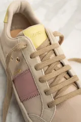 Zapatilla urbana de cuero color beige con detalles en rosa y amarillo.