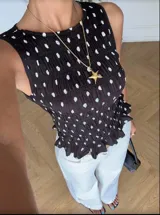 Top negro con lunares blancos, sin mangas, con escote redondo y detalle de fruncido en la cintura.