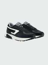 Championes Diesel modelo S-Tyche D, de diseño urbano en color negro con detalles en blanco y gris. Presentan una combinación de malla y gamuza, con el logo de la marca en el lateral y una suela de plataforma robusta.