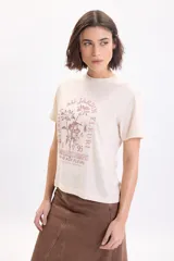 Camiseta de manga corta color crudo con cuello redondo y estampa frontal en tono bordó con motivos florales y texto tipográfico.