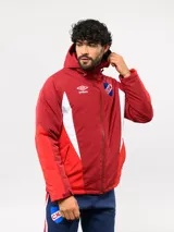 Campera de abrigo Umbro del Club Nacional de Football, con diseño de bloques de color en azul, blanco y rojo. Cuenta con capucha ajustable, cierre frontal y logo de la marca junto al escudo del club en el pecho.