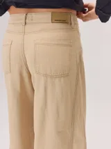 Pantalon de corte ancho y tiro alto, confeccionado en una mezcla de fibras naturales. Presenta un diseño de pierna recta y holgada, con bolsillos traseros aplicados y costuras reforzadas a lo largo de la pierna.