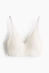 Soutien suave de punto seamless, color beige, con escote en V profundo, tirantes anchos y banda elástica en el bajo. Cuenta con copas con relleno extraíble.