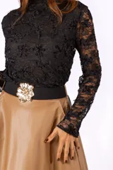 Polera de encaje negro con diseño floral, cuello alto y mangas largas.