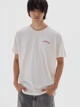 Remera color blanco roto con cuello redondo y manga corta, de calce oversized. Confeccionada en algodón lavado que le da una textura única. Presenta un pequeño logo bordado en el pecho.