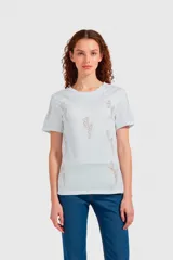 Remera de algodón color blanco con cuello redondo y mangas cortas. Presenta un diseño estampado con múltiples figuras de rayos formadas por pequeños studs metálicos.