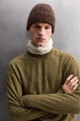 Sudadera de ajuste regular, color verde oliva, con cuello redondo y manga larga. Presenta una textura irregular en el tejido, similar al borreguito o bouclé.