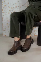 Bota tipo chelsea de punta redonda, confeccionada en una combinación de cuero texturizado y gamuza en tonos marrones. Presenta elásticos laterales negros y una suela track robusta de goma negra.