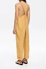 Mono largo de corte recto confeccionado en lino, con escote redondeado y tirantes con detalle de nudo ajustable. Presenta diseño de espalda nadadora y dobladillo en las piernas.